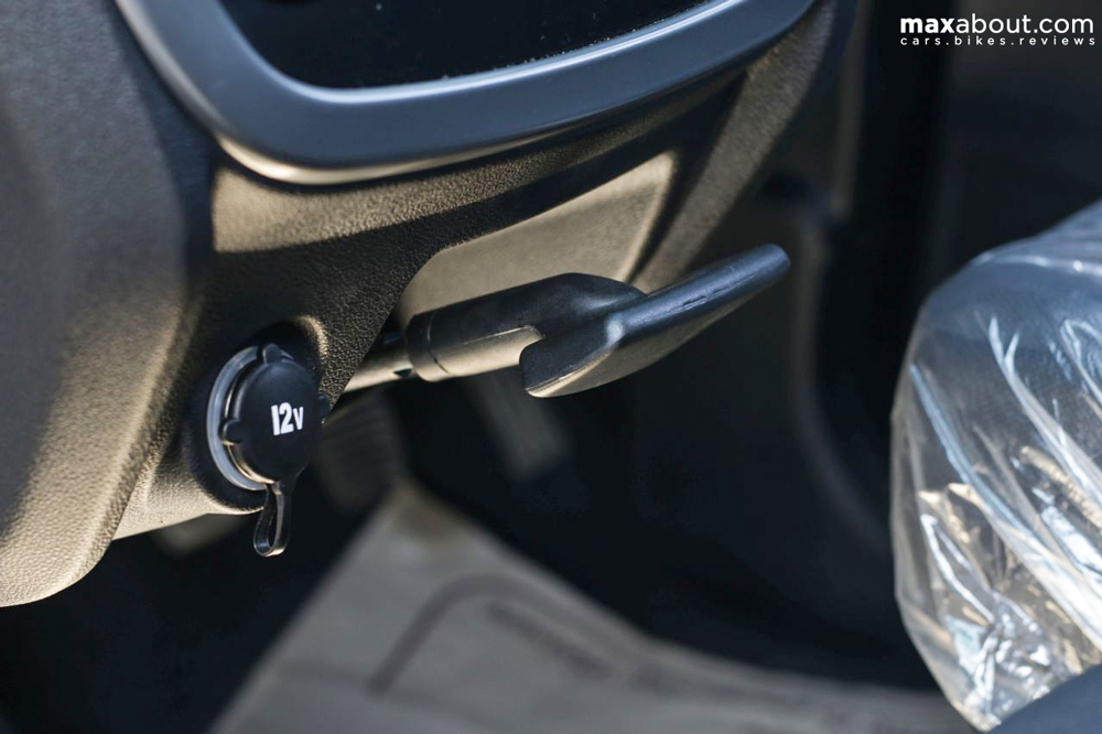 The handbrake on the car is placed right where the dashboard ends. It can be released by twisting the lever and letting it go down. A phone charger can be attached right next to the lever.